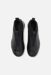 Schwarze Slipper mit strukturierten Oberflächen, die ein hervorgehobenes Logo, einen elastischen Einstieg und ein minimalistisches Design aufweisen.