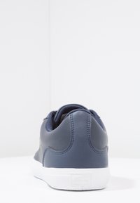 Baskets en cuir bleu marine à texture lisse, col rembourré et semelle en caoutchouc blanche ; logo sur le talon.