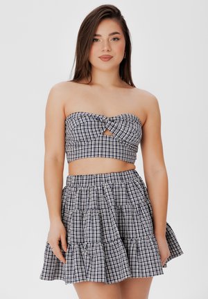 Twee-delige outfit met een strapless, geknoopt top en een gelaagde rok. Marineblauw en wit geruite patroon, katoenen stof en ruches.