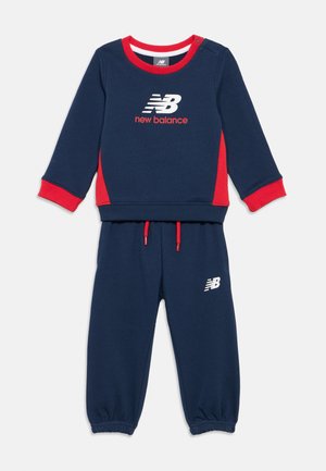 Mørkeblå og rød jakke og bukser sett for småbarn med New Balance-logoer på brystet og venstre buksebein, røde detaljer.
