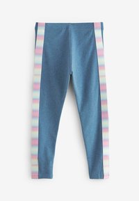 Kék leggings, amelyeken függőleges pasztell szivárvány csíkok futnak le a lábak külső oldalán, fehér háttéren elhelyezve.