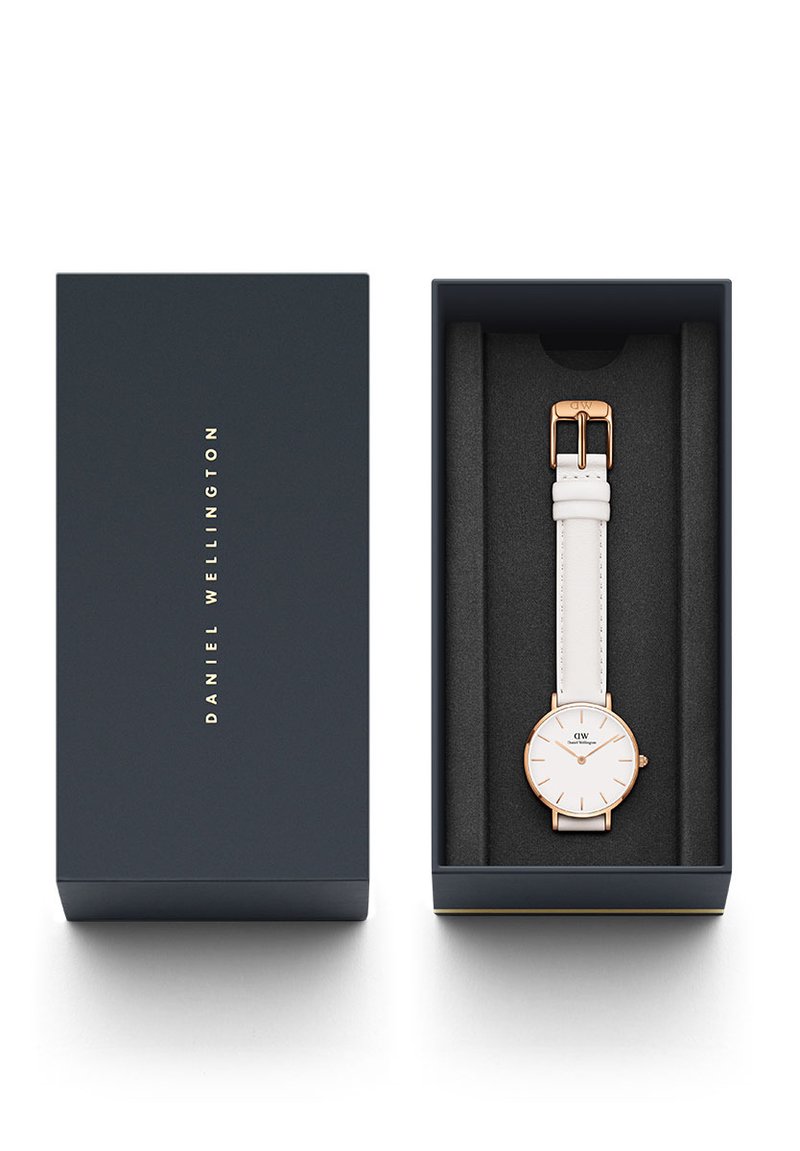 Orologio bianco con quadrante tondo, dettagli dorati e cinturino in pelle, esposto in una scatola blu navy con lettere dorate e interno nero.