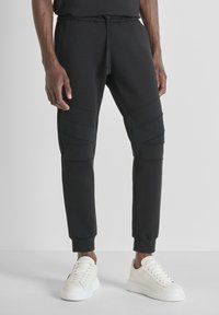 Zwarte joggers van zacht stof, met textuurpanelen en een taps toelopende pasvorm. Ontworpen met een elastische tailleband en elastische enkels.