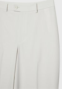 Pantalon écru taille haute avec passants de ceinture, bouton sur le devant et tissu lisse.