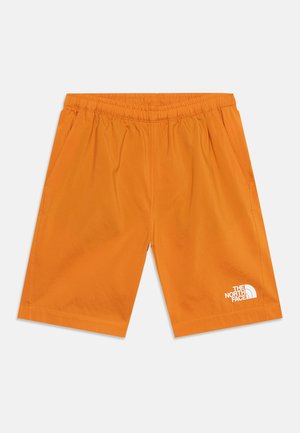 Narancssárga elasztikus derékrészű rövidnadrág oldalzsebekkel és fehér The North Face logóval a bal alsó lábszáron, világosszürke háttéren bemutatva.