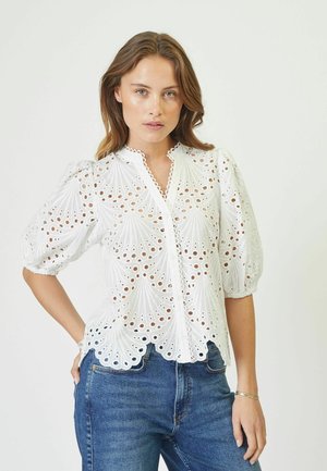 Blusa di cotone bianca con design a occhiali traforati, colletto alto, chiusura a bottoni e maniche puff, con orlo scallop.
