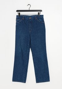 Blå jeans i denim som hänger på en svart galge. Har rak passform, fem fickor, knappstängning och kontrasterande orange sömnad.