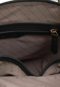 Interno di una borsa a tracolla in pelle nera con una tasca con zip. La fodera presenta un tessuto marrone chiaro con linee verticali sottili e modelli discreti.