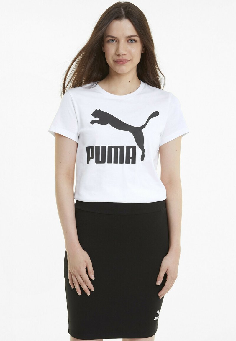 Biała bawełniana koszulka z dużym czarnym logo Puma oraz grafiką kota na przodzie, w połączeniu z dopasowaną czarną spódnicą ołówkową.