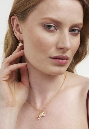 Joyería de tono dorado con un colgante de unicornio en una cadena delicada y pendientes a juego de unicornio, destacando detalles y texturas intrincadas.