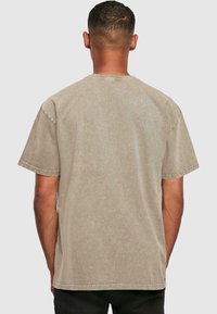Khaki kortærmet t-shirt med en afslappet pasform, blød tekstur og rund hals. Synlige syninger langs kanten og ærmerne.
