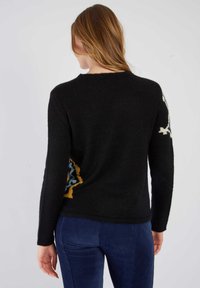 Pull en laine noir avec col rond, manches longues et motifs géométriques colorés sur les côtés. Texture douce avec une coupe décontractée.