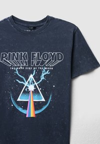 T-shirt in cotone blu navy con il testo "Pink Floyd", una grafica a triangolo con un prisma, un fascio arcobaleno e elementi di design a fulmine.