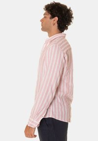 Camicia a maniche lunghe con righe verticali rosa e bianche, colletto con bottoni e maniche con polsini, realizzata in tessuto leggero.