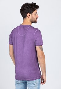 Purple cotton t-shirt with a crew neck, short sleeves, and a relaxed fit. Features subtle stitching details and a soft texture.