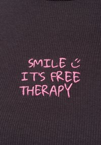Dark gray ribbed fabric top featuring pink embroidered text: “SMILE 🙂 IT'S FREE THERAPY” at the center. Simple and casual design.