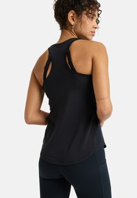 Black athletic tank top with a rounded neckline, racerback design, and textured fabric; paired with navy leggings featuring stitched accents.