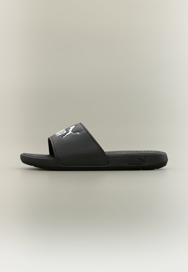 Sandale coulissante noire Puma avec semelle texturée et logo Puma blanc sur une large bride, vue de côté sur fond neutre.