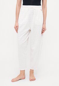 Witte pyjamabroek met een textuurpatroon van herhaalde letters. Losse pasvorm, elastische tailleband met trekkoord en omgeslagen enkels.