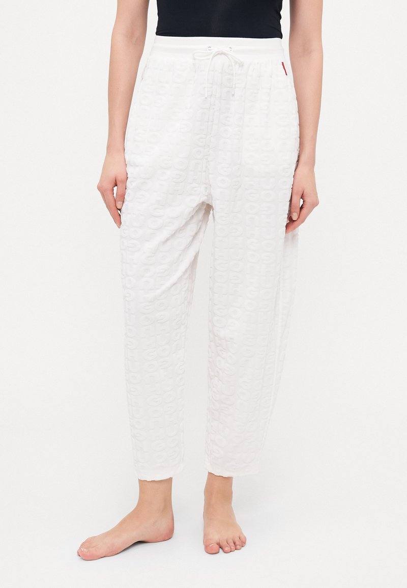 Witte pyjamabroek met een textuurpatroon van herhaalde letters. Losse pasvorm, elastische tailleband met trekkoord en omgeslagen enkels.