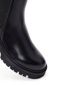 Bottine en cuir noir avec un bout arrondi, panneau latéral élastique et semelle noire robuste avec un profond relief pour une meilleure adhérence.