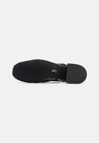 Black sandal with a textured sole, featuring an open design and detailed upper. Sturdy strap and flat heel ensure stability and comfort.