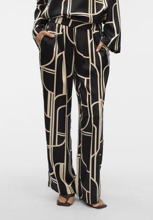 Pantalones de pierna ancha en negro y beige con un patrón geométrico, elaborados en una tela suave. Presentan bolsillos laterales y un diseño de ajuste relajado.