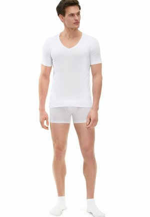 White short-sleeve v-neck t-shirt paired with white boxer briefs, both made of smooth, stretch fabric. Model wearing white ankle socks.