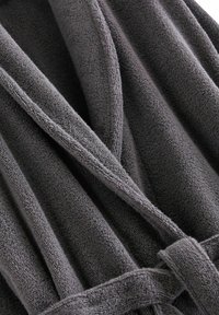 Grå badekåbe lavet af blødt, struktureret stof med synlige folder og en bundet talje. Materialet ser luksuriøst og tykt ud.