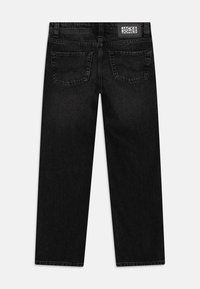 Black denim jeans with a straight-leg cut, featuring back pockets and a logo patch at the waistband. Texture appears smooth with minimal fading.