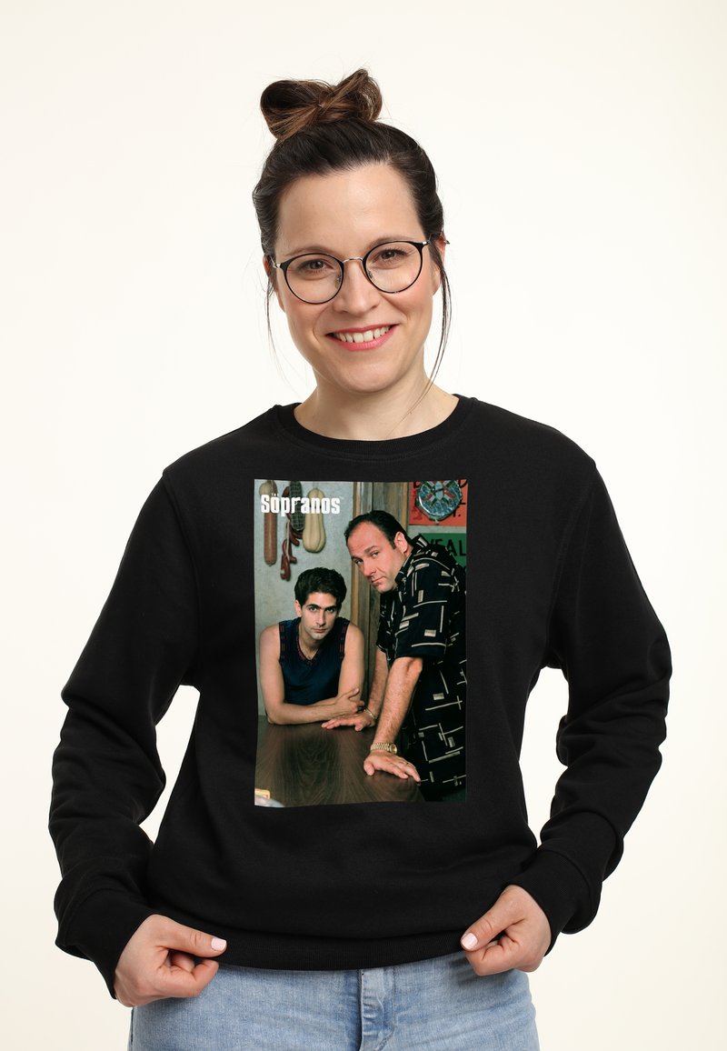 Felpa nera con stampa fotografica di due uomini appoggiati a un tavolo; uno indossa una canotta blu, l'altro una camicia nera a fantasia.