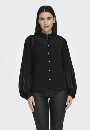 Svart blus med en strukturerad design, som har krage, knappstängning och genomskinliga, puffiga ärmar med texturmaterial.