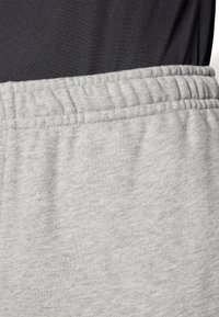 Pantaloni sportivi grigi con vita elastica e un tessuto morbido e testurizzato. Il design è semplice, senza pattern o dettagli visibili.
