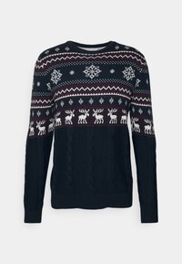 Mörkblå stickad tröja med kabelstickning, med vita snöflingor och renmotiv över bröstet i ett festligt mönster.