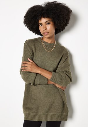 Maglione a maglia verde oliva con superficie testurizzata, vestibilità ampia, polsi e orlo a costine, dotato di spacchi laterali per una maggiore libertà di movimento.