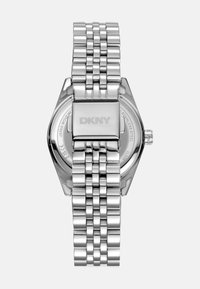 Orologio in acciaio inossidabile silver con cassa esagonale, bracciale a maglie e chiusura liscia. Presenta la scritta "DKNY" incisa sul retro.