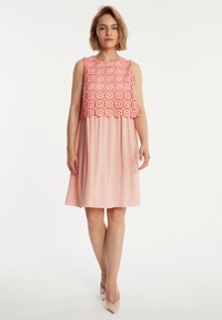 Ärmelloses Kleid mit einem korallfarbenen Spitzentop und einem sanften rosa Rock, mit einem runden Ausschnitt und fließendem Stoff, der oberhalb des Knies endet.