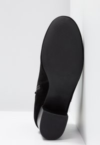 Stivaletto alla caviglia in suede nero con suola in gomma testurizzata, dotato di piccolo tacco e chiusura laterale con zip. Taglia indicata all'interno.