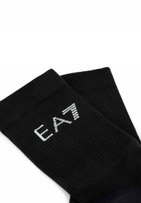 Calze nere in cotone con texture a coste, dotate di un logo bianco "EA7" sul lato. Il design enfatizza semplicità e comfort.