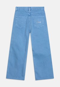 Světle modré široké džíny z denimu, s dvěma zadními kapsami a jemnými detaily šití, s výšivkou loga na pravé kapse.
