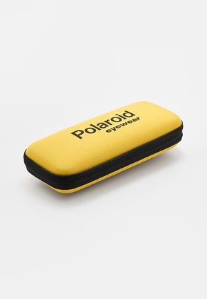 Custodia rigida gialla per occhiali Polaroid con cerniera nera e scritta del logo nera in alto, posizionata su uno sfondo bianco.