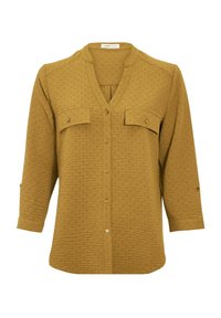 Blouse à manches longues en maille texturée de couleur jaune moutarde, avec un boutonnage à l'avant, deux poches poitrine avec rabat et un col rond avec une petite fente en V.