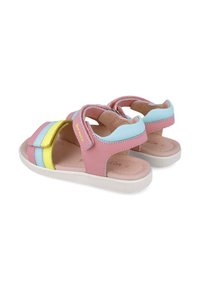 Sandalias de cuero rosa con correas divididas, presentando rayas amarillas, azules y verdes. Suela plana blanca con agarre texturizado; cierre de gancho y lazo.