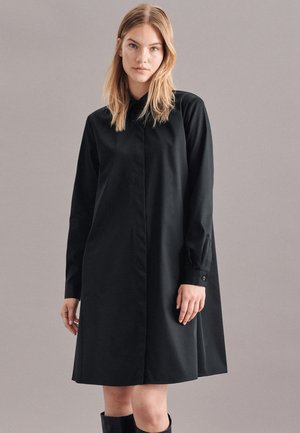 Zwarte, lange mouw jurk met kraag, met een rechte snit en knoopdetails op de manchetten. Gladde, lichte stof.