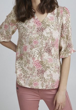 Blumenbluse in Creme mit rosa und grünen Mustern, mit V-Ausschnitt und kurzen Puffärmeln. Glatter Stoff mit leichter Textur.