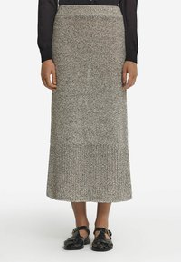 Stickad midi kjol i ett texturerat grått och svart mönster med en ribbad fåll. I kombination med svarta, remmade platta skor.