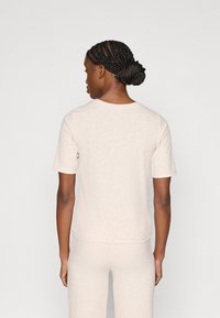 Ανοιχτό μπεζ ριπ κοντομάνικη μπλούζα με στρογγυλή λαιμόκοψη και λεπτή εφαρμογή. Το ύφασμα έχει απαλό υφή και ελάχιστες λεπτομέρειες στο σχέδιο.