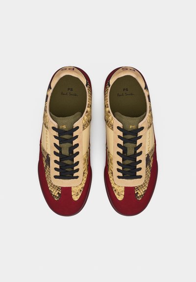 Ζευγάρι αθλητικών παπουτσιών Paul Smith με κόκκινα δέρματα από σουέντ στα δάχτυλα, μπεζ δερμάτινα πάνελ, υφή φιδιού και μαύρα κορδόνια, σε θέα από πάνω.