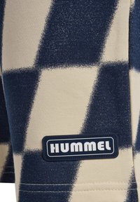 Marinblå och creamfärgade rutiga sportshorts tillverkade av mjukt tyg, med en svart "HUMMEL" logotypapplikation och synliga sömmar.
