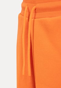Orange bomulds-sweatpants har en ribbet talje og snøre, med en glat tekstur og en sidelomme.